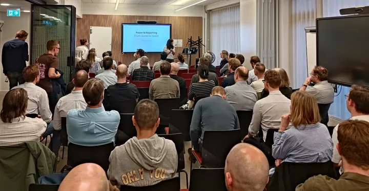Publikum til et MsBIP-møde, hvor en oplægsholder præsenterer "Power BI Reporting – From Good to Great"